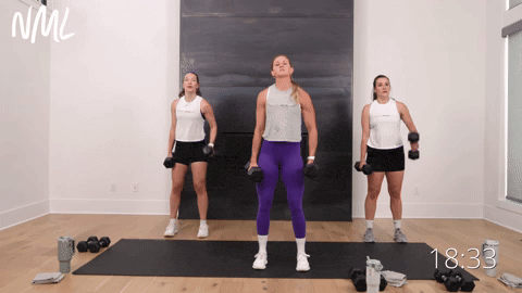 three women performing alternating bicep curls and shoulder presses with dumbbells in a full body workout