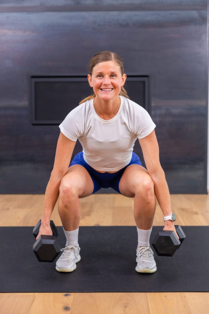 woman performing a dumbbell squat as part of at home full body workout