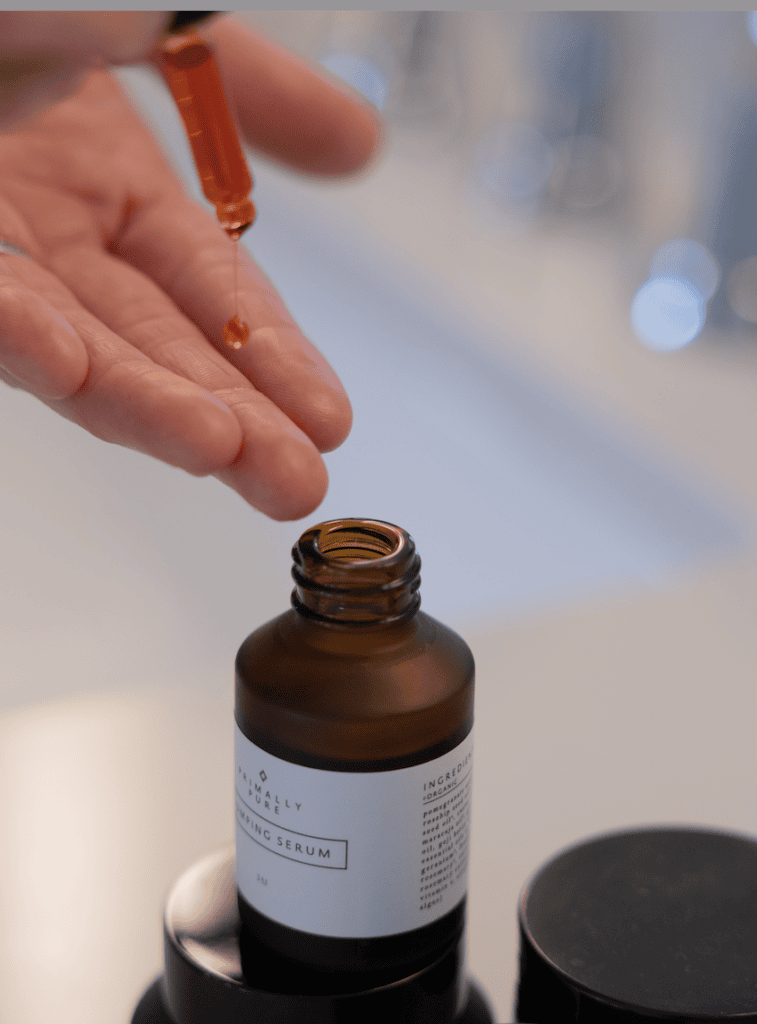Women using Plumping Serum in her bathroom. As part of the best skincare routine products from primally pure.
