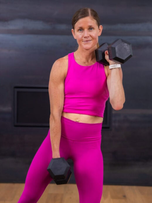 woman holding one dumbbell front racked and the other at her hips in a full body workout