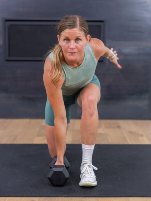 woman holding a low lunge with one dumbbell in a leg day workout