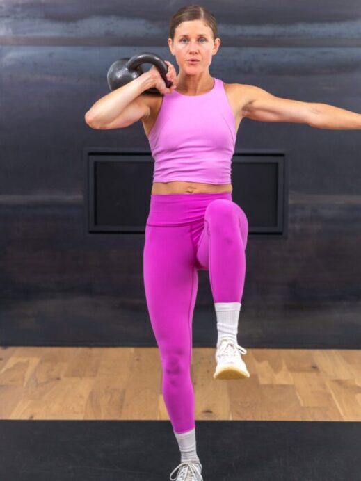 woman standing with kettlebell on shoulder