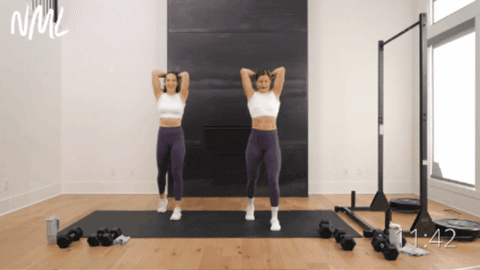 standing women performing overhead tricep extensions