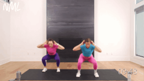 two women performing a squat and standing crunch as part of beginner hiit workout