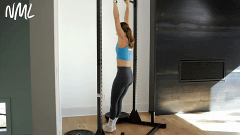 woman hanging on the bar as part of an assisted pull up tutorial at home