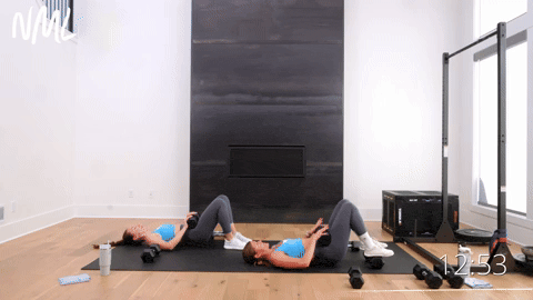 two women performing dumbbell glute bridges in a full body workout with weights