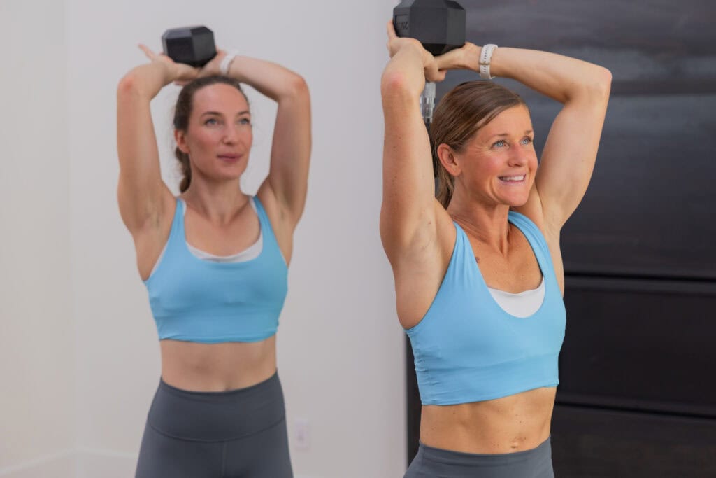 two women performing overhead tricep extensions in a full body workout