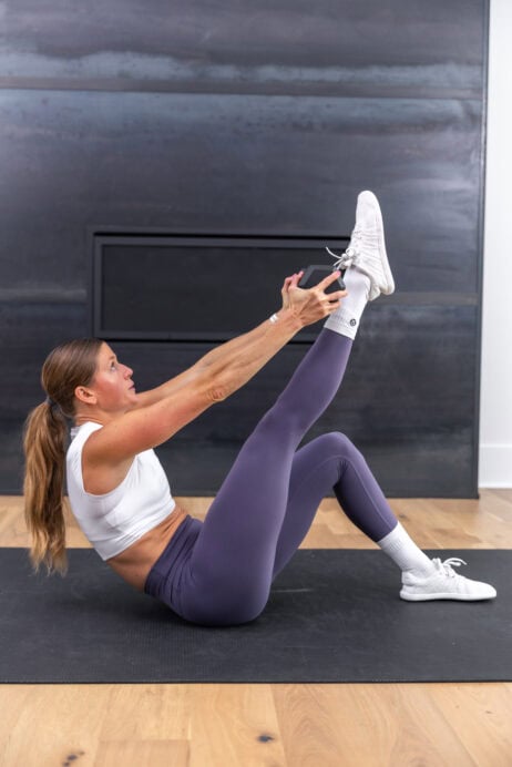 woman performing a weighted sit up in a total body and abs workout