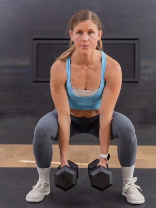 woman performing a dumbbell squat in a full body workout