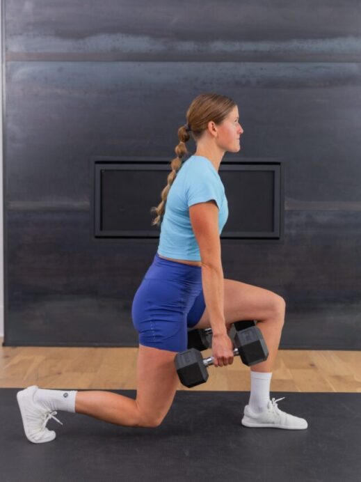 woman performing a dumbbell lunge as part of a leg workout