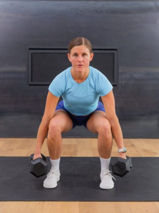 woman performing a dumbbell squat as part of a leg workout