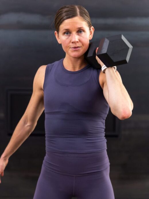 woman holding one dumbbell front racked at her shoulder in a hiit workout routine