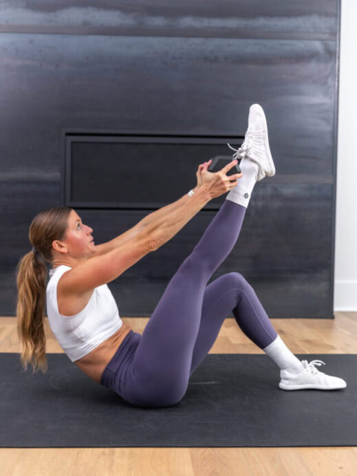 woman performing a weighted sit up in a total body and abs workout