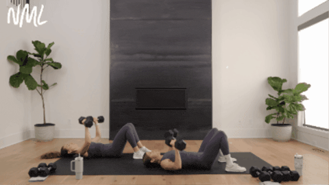 two women laying on their backs performing chest presses