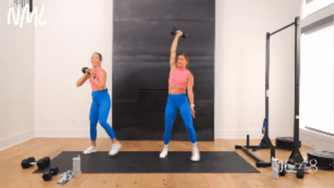 Two women performing a windmill with dumbbell in right hand into a 45 degree lateral lunge.