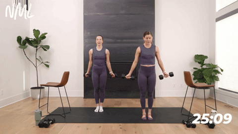 two women performing a narrow squat and bicep curl in a barre workout