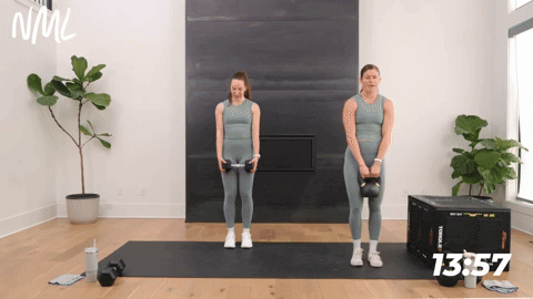 two women performing a lateral lunge clean and overhead press as part of a full body kettlebell workout