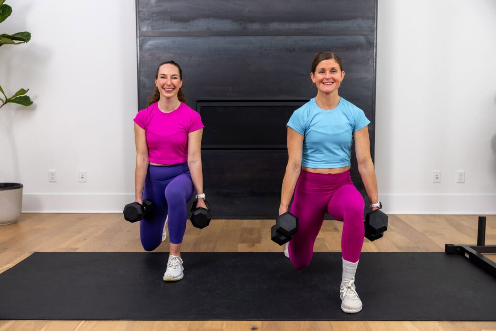 two women performing a dumbbell split lunge as part of the best circuit training exercises