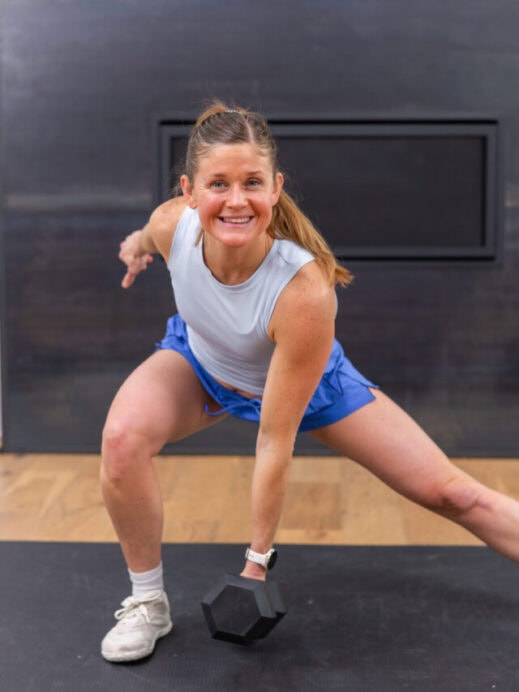 woman performing a lateral lunge with dumbbells in a quick leg workout
