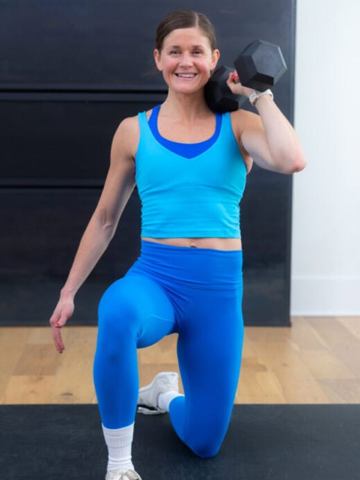 woman performing a kneeling single arm press in a full body workout for women