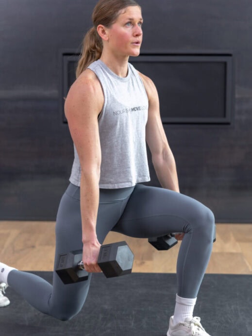 woman performing a dumbbell lunge as part of the best total body exercises