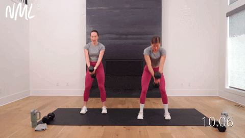 two women performing a dumbbell swing to single arm shoulder press in a cardio workout with weights