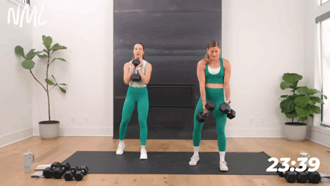 two women performing staggered squats with dumbbells in a leg and glute workout