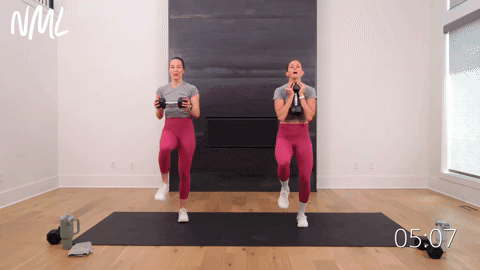 two women performing weighted high knees in a cardio workout with weights