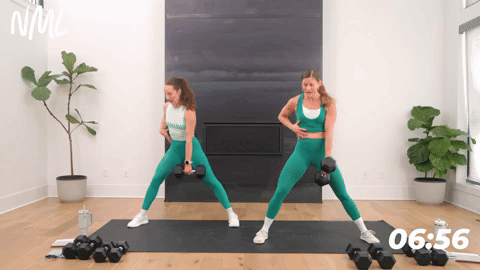two women performing lateral squats with dumbbells in a leg and glute workout
