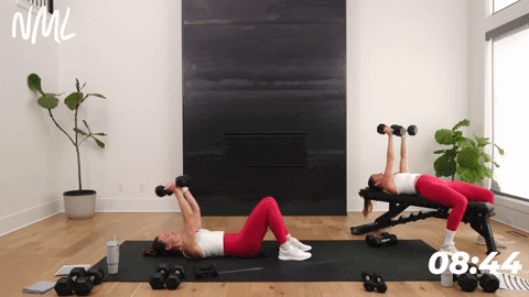 two women performing skull crushers with dumbbells in a chest shoulders and triceps workout