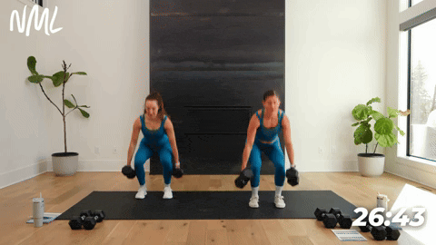 Two women performing 2 narrow squats into 2 wide squat with dumbbell in each side. Full body ab workout