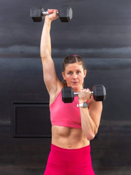 woman performing a single arm overhead press with a dumbbell in a push day workout