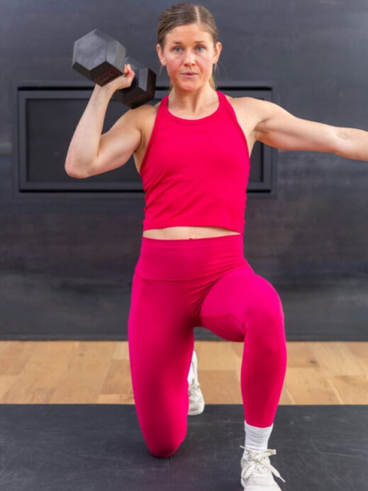 woman performing a kneeling overhead press in a strength workout for runners