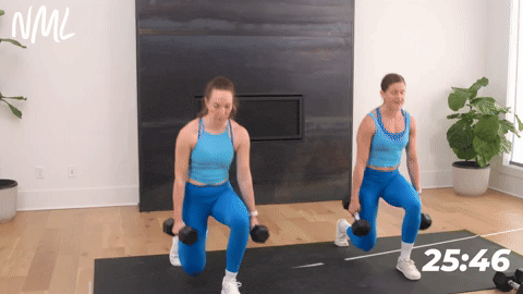 two women performing a front lunge into a 45 degree lunge holding two dumbbells