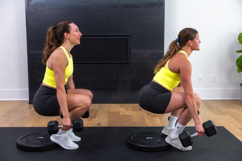 two women performing a heels elevated squat as part of quad and glute workout