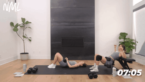 women performing a dumbbell hip thrust as part of glute and hamstring workout