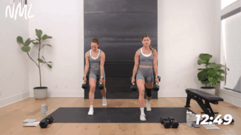 standing women performing a staggered deadlift and lunge combination exercise