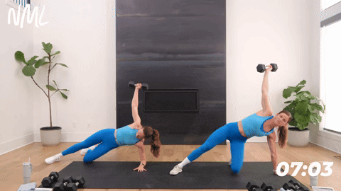 one women performing ½ Kneeling to Side Plank Kick Out. one women holding a side plank with dumbbell over her shoulder. 