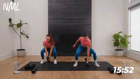 two women performing a touch and go jack with a dumbbell in a full body hiit workout