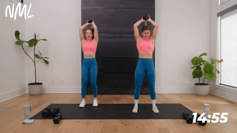 two women performing overhead triceps and a march in a full body hiit workout