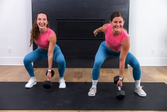 two women holding a low squat performing a touch n go dumbbell squat jack in a full body hiit workout