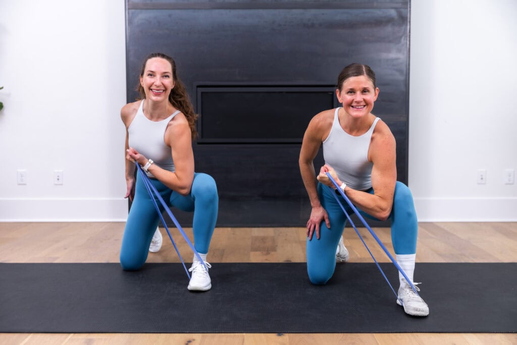Two women performing a Kneeling Concentration Curl | Resistance Band Workout