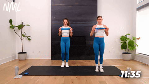 Two women performing a Lateral Lunge and Shoulder Press with a resistance band.