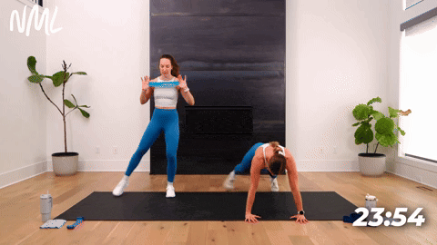 One women performing a Push Up into a toe tap and one women performing a standing chest press out and top tap.