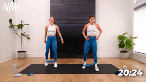 Two women performing staggered squats with a resistance band.