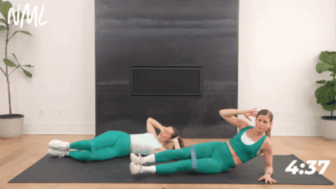 2 women performing a side lying leg lift and double knee crunch as part of abs and booty workout