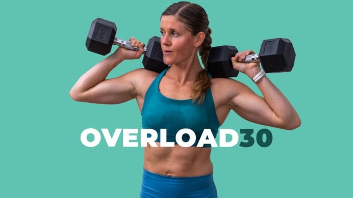 Woman holding dumbbell at shoulders as part of progressive overload workout plan