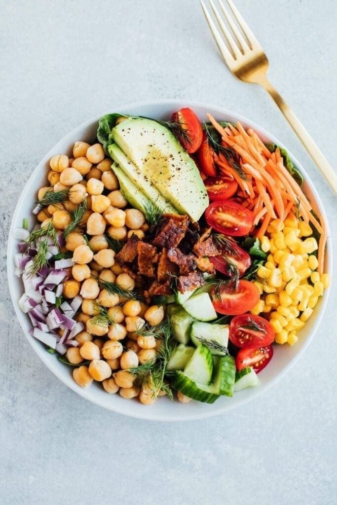 Vegan Cobb Salad with chickpeas, onions, cucumbers, tomatoes, corn and carrots.