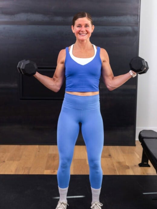 woman performing a wide bicep curl with dumbbells in a back and bicep workout
