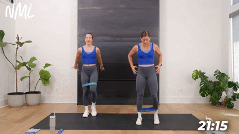 two women performing banded side step squats in a booty band workout